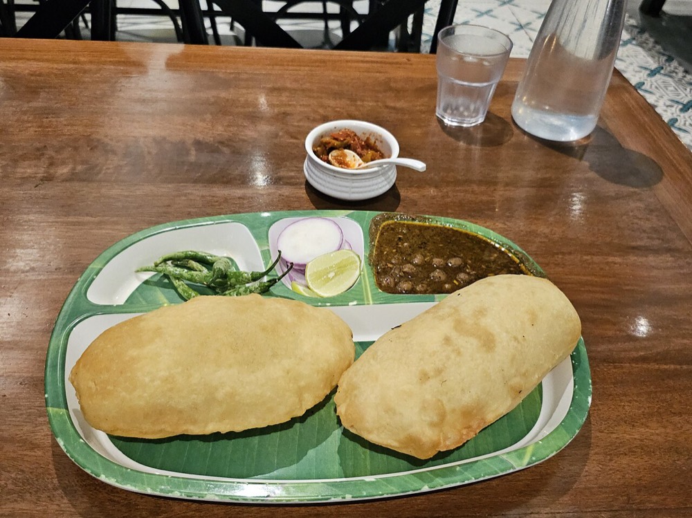 Chole bhature: two puffy bhature with a bowl of chole